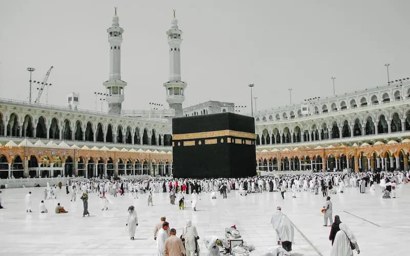 Pilgrims wearing white ihram garments walking near the Kaaba during Umrah rituals in Makkah